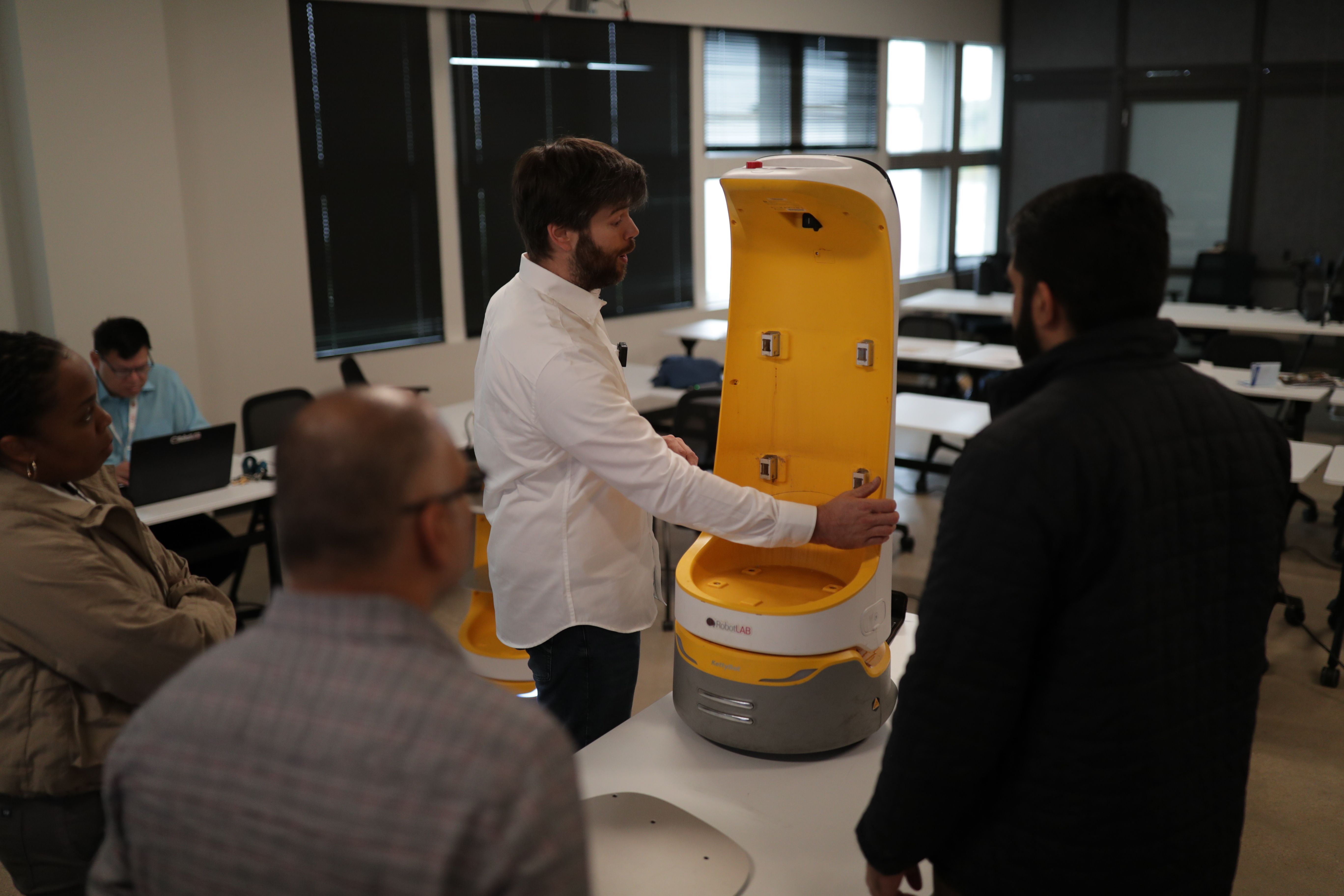 A RobotLAB specialist demonstrating a service robot to a group during a hands-on training session